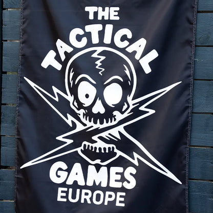 A black banner featuring a white skull and crossed lightning bolt graphic with the text 'THE TACTICAL GAMES EUROPE',

