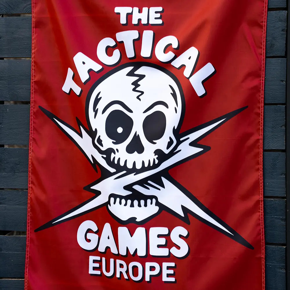 A red vertical banner featuring a white skull and crossed lightning bolts with the text 'THE TACTICAL GAMES EUROPE', 