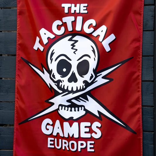 A red vertical banner featuring a white skull and crossed lightning bolts with the text 'THE TACTICAL GAMES EUROPE', 