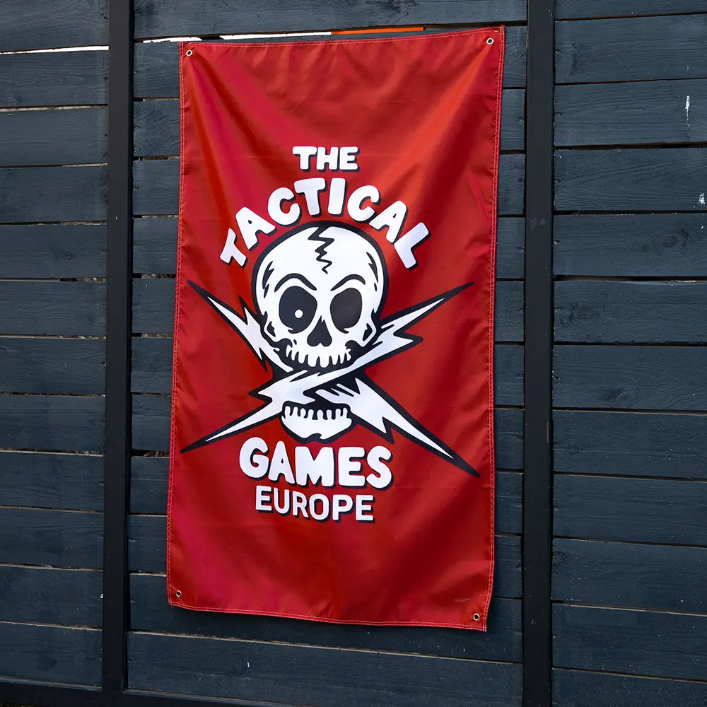 A red vertical banner featuring a white skull and crossed lightning bolts with the text 'THE TACTICAL GAMES EUROPE', 