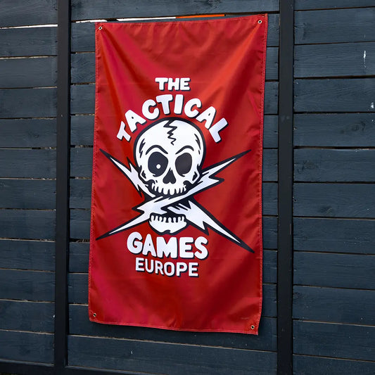 A red vertical banner featuring a white skull and crossed lightning bolts with the text 'THE TACTICAL GAMES EUROPE', 