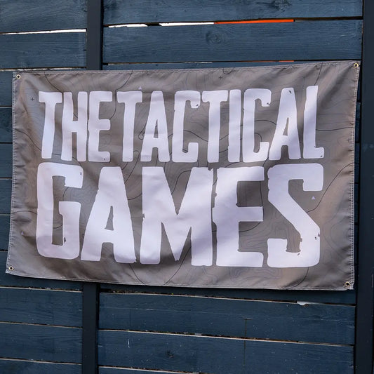 A rectangular gray horizontal  banner with the words 'THE TACTICAL GAMES' in large white block letters, 